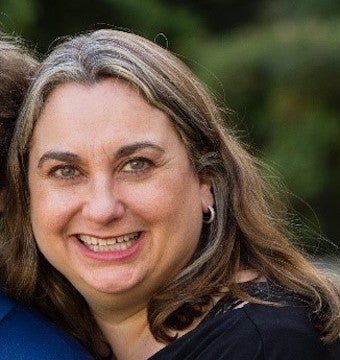 Michelle Popowitz, a woman with long, straight brown hair, smiles at the camera.