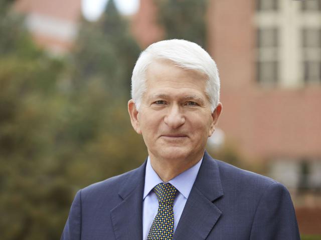 A man with short silver hair in a suit and tie.