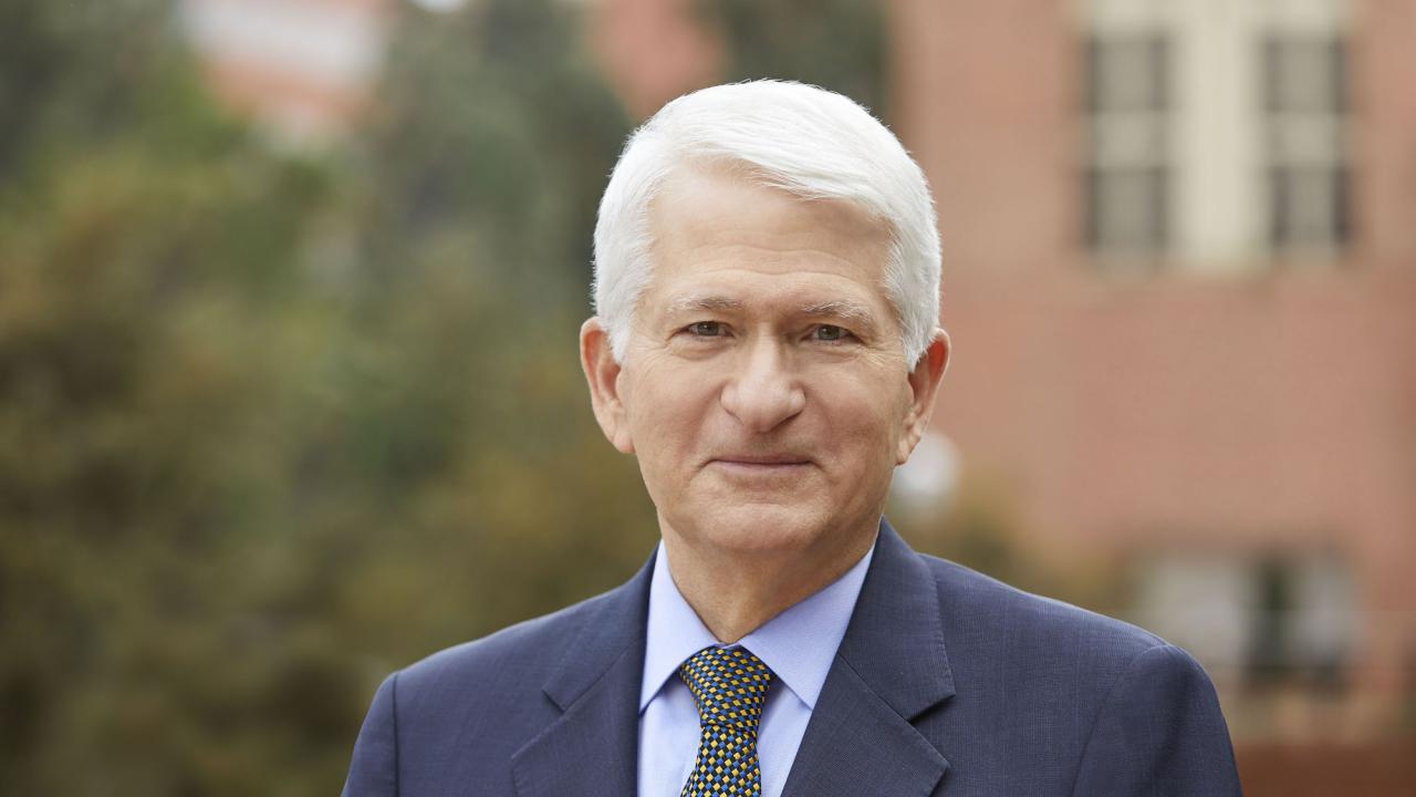 A man with short silver hair in a suit and tie.