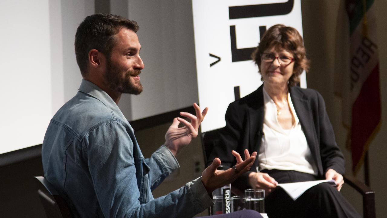 Kevin Love and Michelle Craske speak at a panel stage.