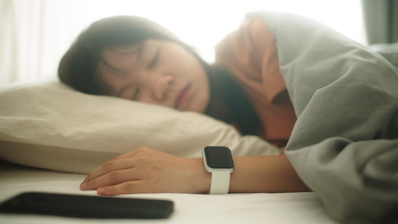 Woman sleeping with smart watch and cell phone