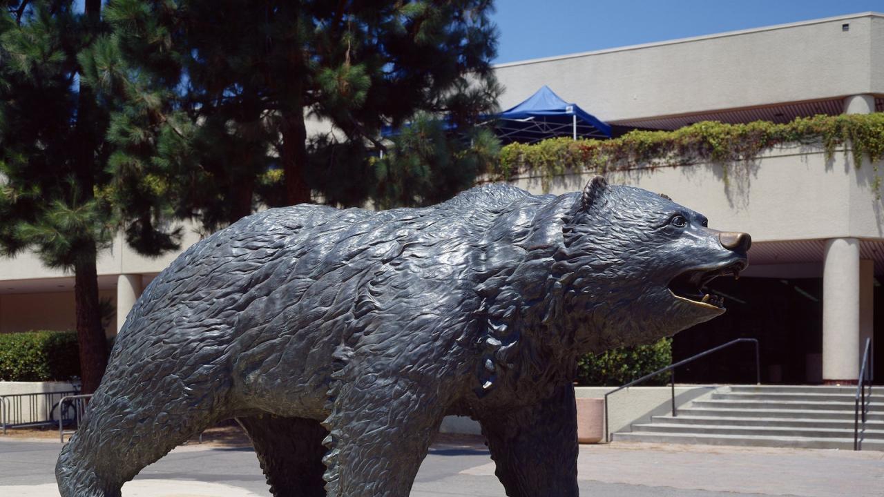 Bruin Bear statue at Bruin Plaza with trees in the background.