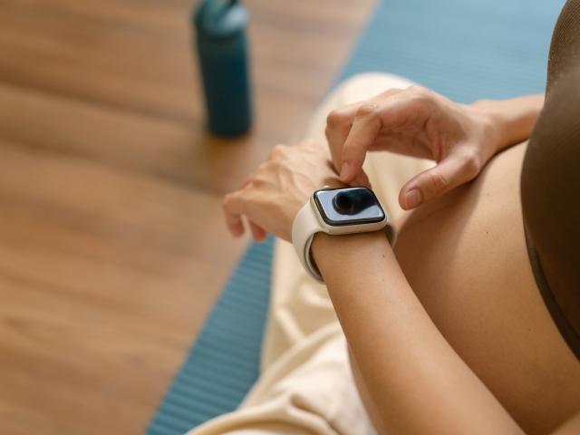 A pregnant woman taps an Apple Watch