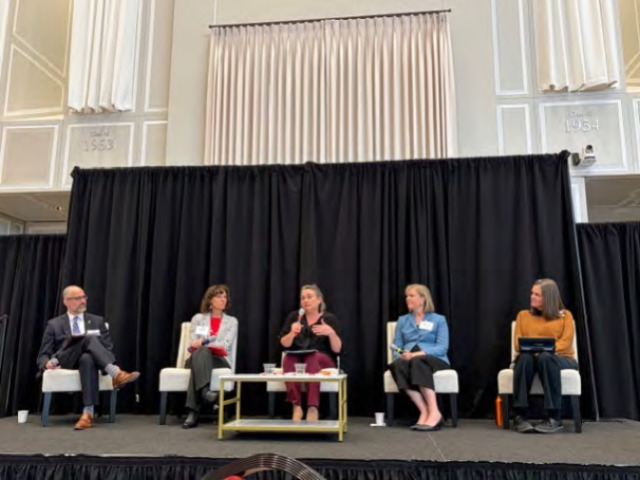 Eric Chapman, Rebekah Hersch, Michelle Popowitz, Megan Barnett, and Cinda Christian sit on an on-stage panel.