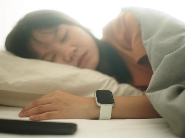Woman sleeping with smart watch and cell phone