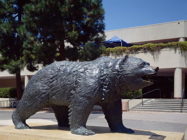 Bruin Bear statue at Bruin Plaza with trees in the background.