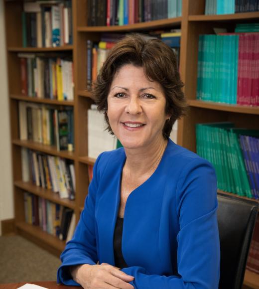 Michelle Craske, a woman with short brown hair, smiles at a university desk.