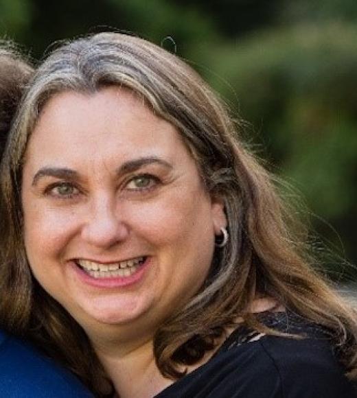 Michelle Popowitz, a woman with long, straight brown hair, smiles at the camera.