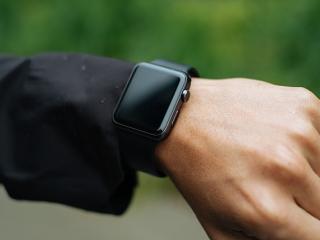 A hand wearing an Apple watch, screen off.