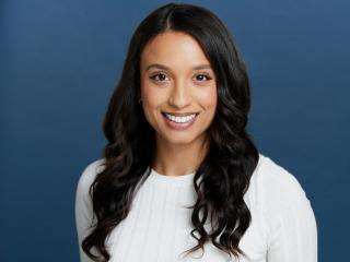 Headshot of a woman with a medium complexion and long dark hair smiling.