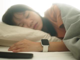 Woman sleeping with smart watch and cell phone